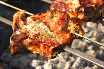 Pork steak with spicy on the skewers are cooking outdoor. Summer family picnic concept. Close up, selective focus, top view.