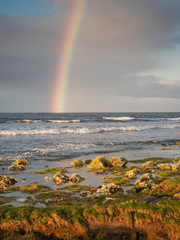 Rainbow over Atlantic ocean, Galway bay, Ireland, Burren mountains in the background. Cloudy sky.