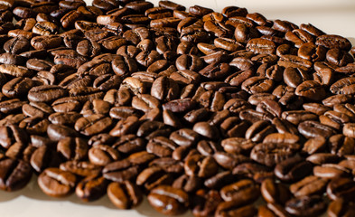 A scattering of coffee beans close-up with glitter lit to the right