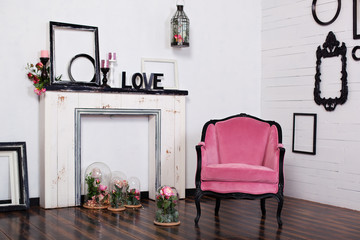 Vintage velor armchair, in a bright room and an artificial fireplace. Interior attic with wooden...