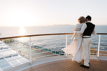 Young beautiful couple on the deck of a cruise liner in the sea - obrazy, fototapety, plakaty