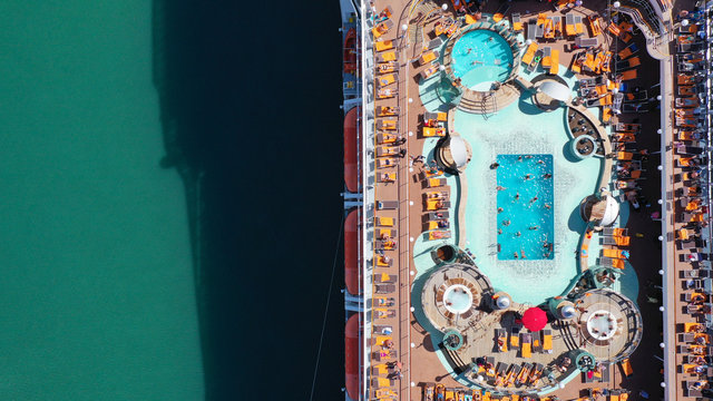Aerial top view photo of crowded open sun deck with large pool and facilities of cruise ship liner docked in port of Piraeus, Attica, Greece