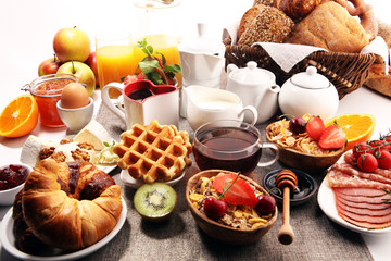 Huge healthy breakfast on table with coffee, orange juice, fruits, waffles and croissants. Good morning concept.