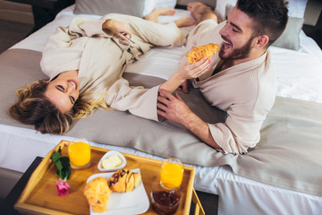 Young happy couple having breakfast in luxury hotel room.