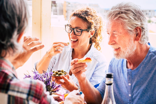 People having fun together during lunch in friendship - mixed ages woman and an eating in family activity - caucasian adults laugh and smile for nice activity