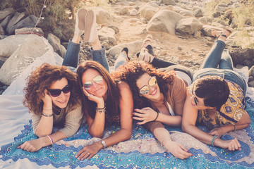 Group of people happy friends young caucasian cheerful women lay down on the ground and enjoy the friendship together having fun - middle age ladies laughing and smiling