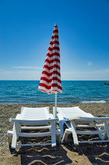 Sun loungers and parasols on the beach. Coast of the Black Sea in Sudak, the Crimean Republic