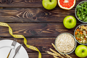 Diet for weight loss concept with measuring tape, greenary and oat on wooden background top view copy space