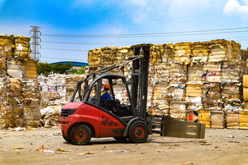 Fototapeta na wymiar Worker drive forklift working factory recycle industry cardboard garbage, paper waste after pressing in hydraulic baling garbage press machine to a square dense for transportation to recycle factory 