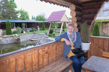 Portrait of a mature woman sitting in a wooden gazebo on a bench
