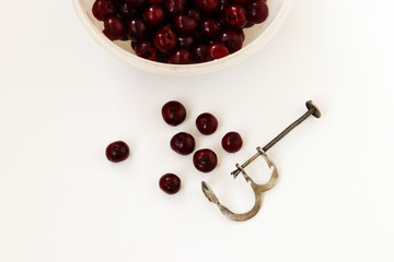 A pitted cherry is located in a bowl on a white background, Removal of bones from cherries by...