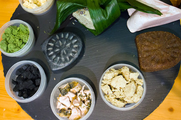 Plastic boxes with pieces of natural cosmetic products and handmade soap arranged on a wooden board