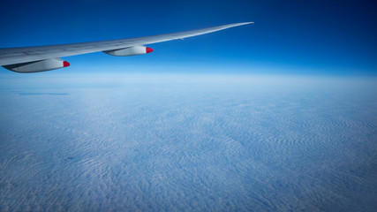 Close up of window with airplane wing. Beautiful cloudscape with clear blue sky.