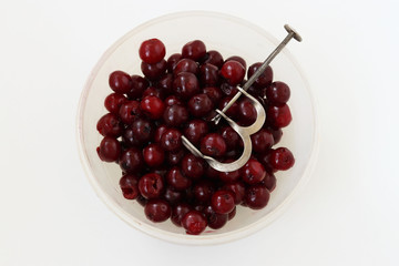 Fresh, seedless cherry is located in a bowl on a white background, Removal of bones from cherries by special adaptation