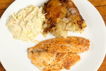 Overhead view of Tilapia Dinner with Homefries and Coleslaw on White Platter with Copy Space