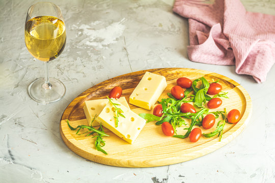 Cheese, tomatoes and arugula on the wooden plate
