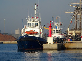 view of a tugboat moored in the harbor next to fishing boats