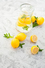 Homemade refreshing lemonade in decanter close-up and copy space. Lemonade from lemons, mint, ice.