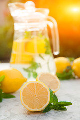Fototapeta na wymiar Homemade refreshing lemonade in decanter close-up and copy space. Lemonade from lemons, mint, ice.