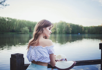 Attractive young woman relaxing outside in park with sunset in background. 