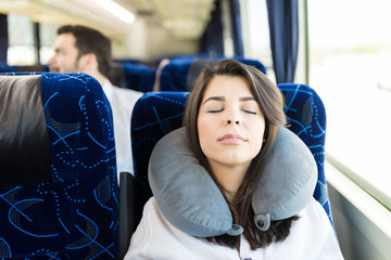 Woman sleeping with a neck pillow while traveling by bus
