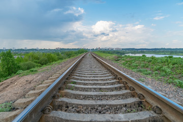 train tracks near the city with a beautiful blue sky with clouds, lake