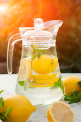 Homemade refreshing lemonade in decanter close-up and copy space. Lemonade from lemons, mint, ice.