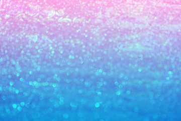 Blurred bokeh light blue pink holographic background, Christmas and New Year holidays background. Party concept. Festive holiday bright backdrop. Defocused.