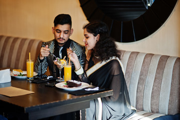 Lovely indian couple in love, wear at saree and elegant suit, posed on restaurant.