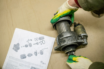 Mechanic repairing a starter on a wooden table with instructions