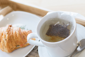 tea bag brewed in a mug of hot water. Delicious breakfast with croissant