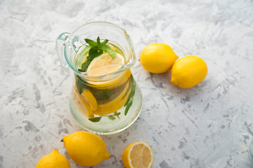 Homemade refreshing lemonade in decanter close-up and copy space. Lemonade from lemons, mint, ice.