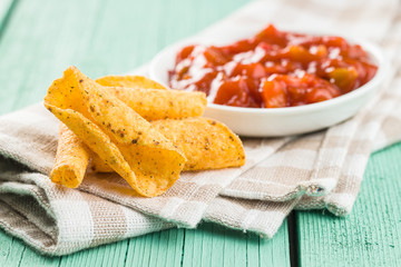 Rolled mexican nacho chips and salsa dip.