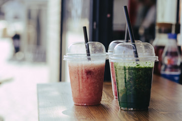 Colorful Sweet smoothie in plastic cups on wooden table