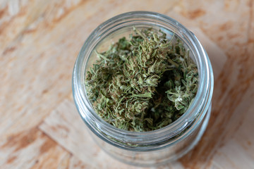 a glass jar filled with marijuana tops, macro