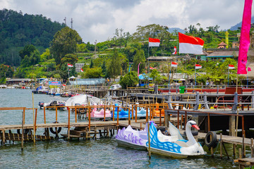 Fototapeta na wymiar Pura Ulun Danu Bratan wooden port at lake with dove boats, Bedugul, Indonesia.