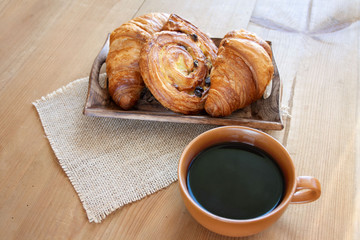 Sweet breakfast: black coffee, croissants and a roll with raisins