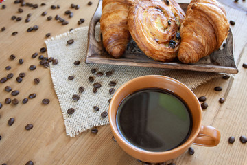 Sweet breakfast: black coffee, croissants and a roll with raisins
