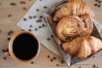 Sweet breakfast: black coffee, croissants and a roll with raisins