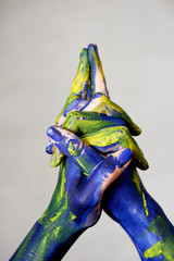 Hands in blue paint with yellow accents, hands of the artist and creative person. Yoga for hands