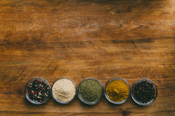 Variety of spices in round glass bowls - ground ginger, hops-suneli, kari, black pepper and mix