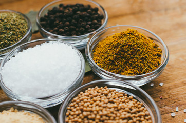 Variety of spices in round glass bowls - ground ginger, hops-suneli, kari, black pepper and mix