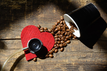 on the old blackboard is a red heart on which the coffee grains. Near the stethoscope. Concept - harm and benefits from drinking coffee