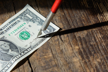 A fountain pen clings to a $ 1 bill against the background of an old wooden board. Shadow from the handle. Concept - fake money