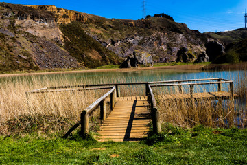 a wooden walkway over a lagoon in La Arboleda, in Biscay