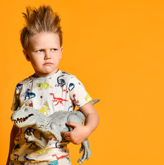 little boy with a funny, disheveled hair holds the toy plastic dinosaur as a portrait.