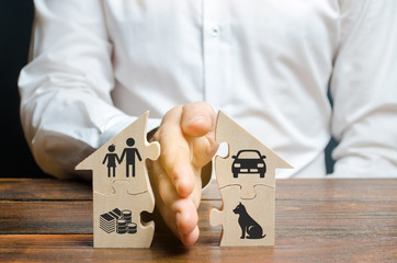 A man shares a house with his palm with images of property, children and pets. Divorce concept, property division process. Marriage contract, custody of children. The layer's services