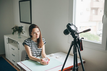 Girl videoblogger or beauty blogger records video for subscribers how to use the cream and talks...