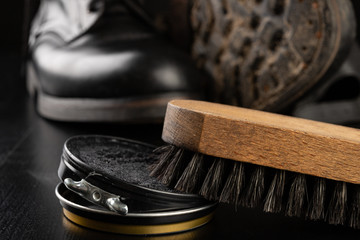 Shoe polish, brush and black military boots. Polishing and cleaning shoes on a black table.