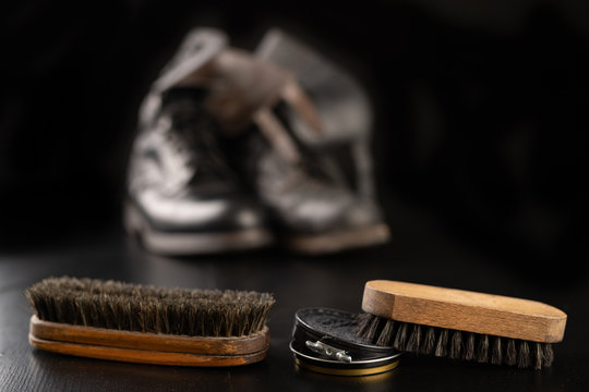 Shoe polish, brush and black military boots. Polishing and cleaning shoes on a black table.